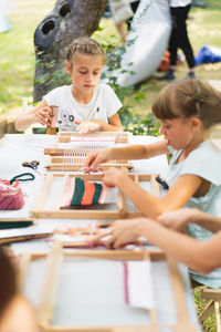 Girl weaving small rug with pattern at masterclass on weaving.