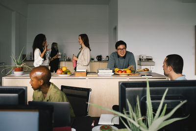 Male and female corporate colleagues talking to each other at office