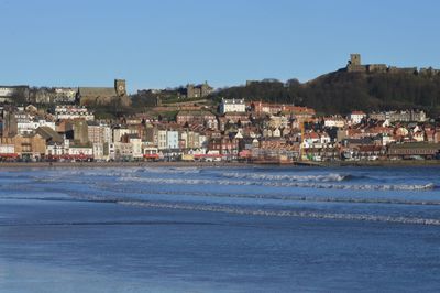 Town in front of sea against clear blue sky