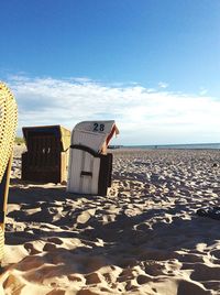 Hooded beach chair on shore against sky