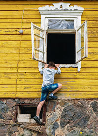 A kid trying to climb through the opened window