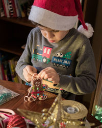 Young boy decorating christmas ornaments at home