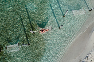 Attractive woman relaxing on a hammock over the water. air view.