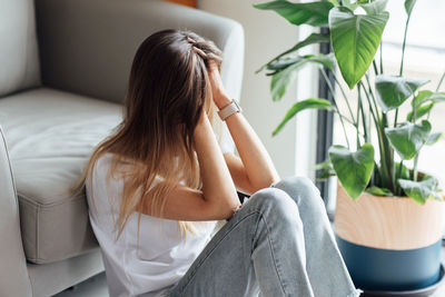 Young woman sitting on sofa at home