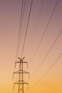 Low angle view of power lines against sky at sunset