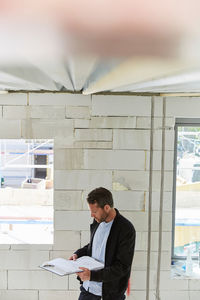 Mature architect reading document at incomplete building