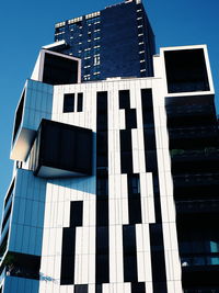 Low angle view of modern building against clear blue sky