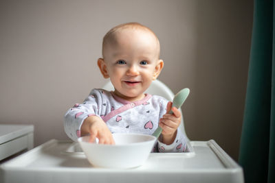 Portrait of cute baby boy holding bowl on table