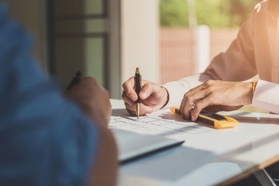 Cropped hands of businessmen working at desk in office