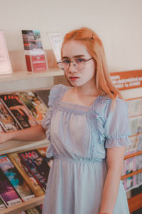 Portrait of young woman standing by shelf in store