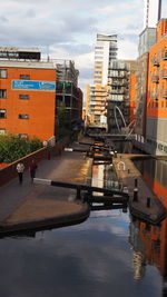 Canal amidst buildings in city against sky