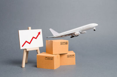 Airplane plane takes off behind stack of cardboard boxes and stand with red up arrow.