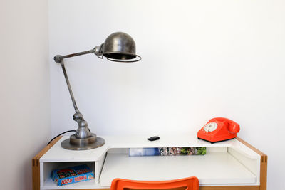 Close-up of electric lamp on table against wall at home
