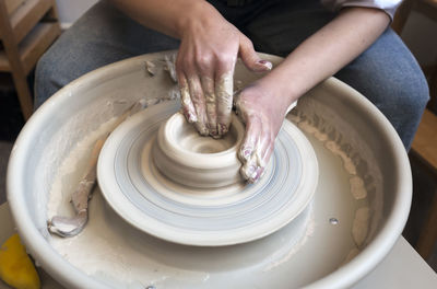 A potter works on a fast spinning potter's wheel and makes a bowl. creating ceramics.