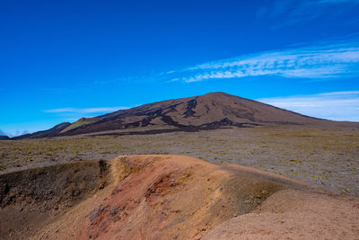 Scenic view of arid landscape against blue sky