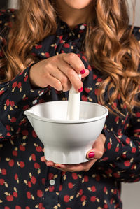 Midsection of woman holding coffee in front of cup