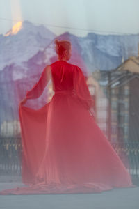 Rear view of woman with arms raised against sky