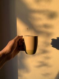 Hand holding coffee cup against wall