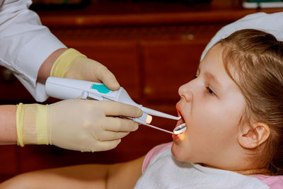 Cropped hands of dentist examining girl mouth