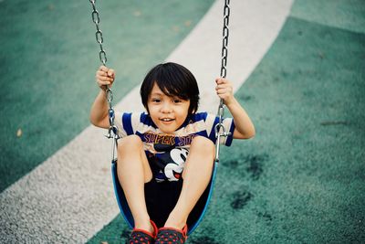 Portrait of a smiling girl sitting on swing at playground