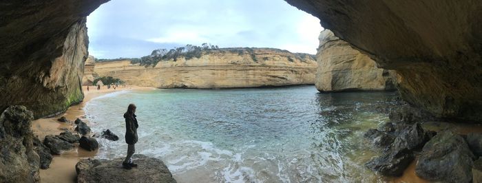 Woman standing by river seen through cave