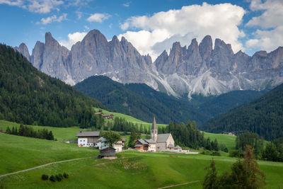 Houses on field by mountains against sky