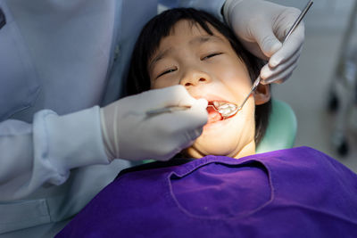 Hand of doctor dentist is working on the teeth of dentist using ultraviolet light on the boy's teeth