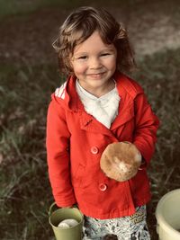 Close-up of cute girl standing on field with a mushroom 