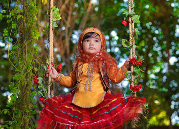 A two-year-old girl wearing a bakhtiari ethnic dress riding on a swing