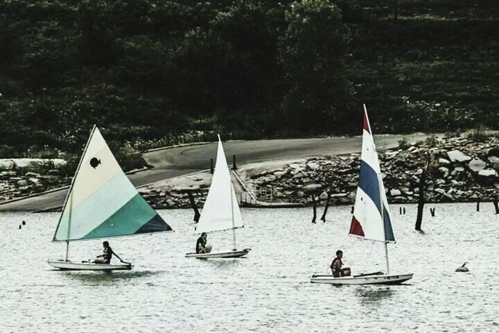 transportation, nautical vessel, leisure activity, lifestyles, mode of transport, flag, boat, beach, patriotism, vacations, travel, sea, men, identity, water, day, high angle view, large group of people, outdoors