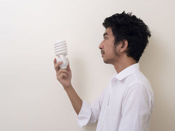 Side view of young man standing against white background