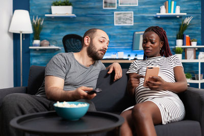 Young woman with men using smart phone at home