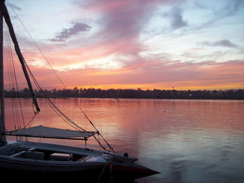 Sailboats moored on sea against sky during sunset
