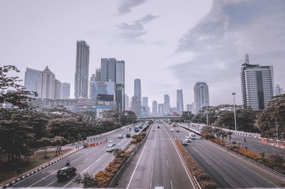 Vehicles on road amidst buildings in city against sky