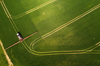 Top down view of the tractor spraying the chemicals on the large green field