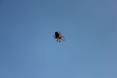 Low angle view of helicopter against clear blue sky