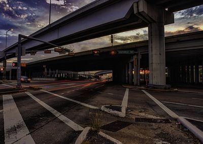 Railroad tracks by bridge in city against sky