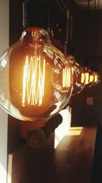 Close-up of illuminated light bulb hanging at night