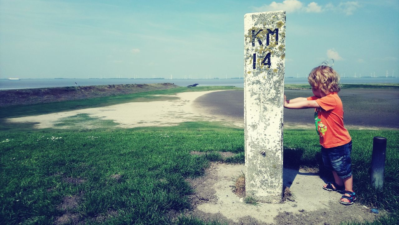 SIDE VIEW OF BOY STANDING ON RIVERBANK