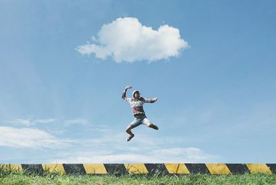 Low angle view of man jumping against sky