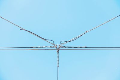 Low angle view of power lines against clear blue sky