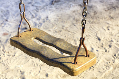 The seat of an old children's swing on a metal chain.