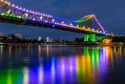 Illuminated bridge over river at night