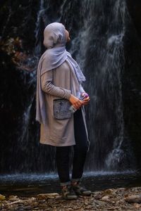 Woman standing by waterfall in forest