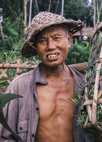 Vertical portrait of a south asian balinese senior men wearing a traditional cone-shaped hat 