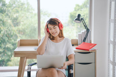 Young woman using phone while sitting on table