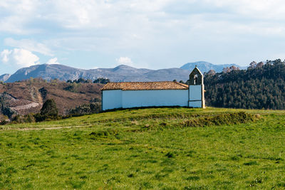 Small chapel in meadow against the mountains and blue sky, asturias. spain