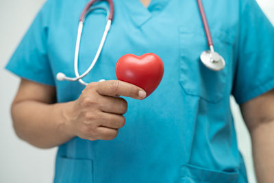 Doctor holding a red heart in hospital ward, healthy strong medical concept.