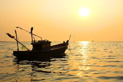Fishing boat in sea against sky during sunset