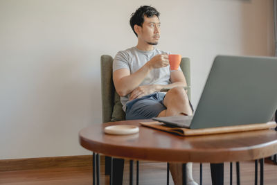 Young man using mobile phone while sitting on table